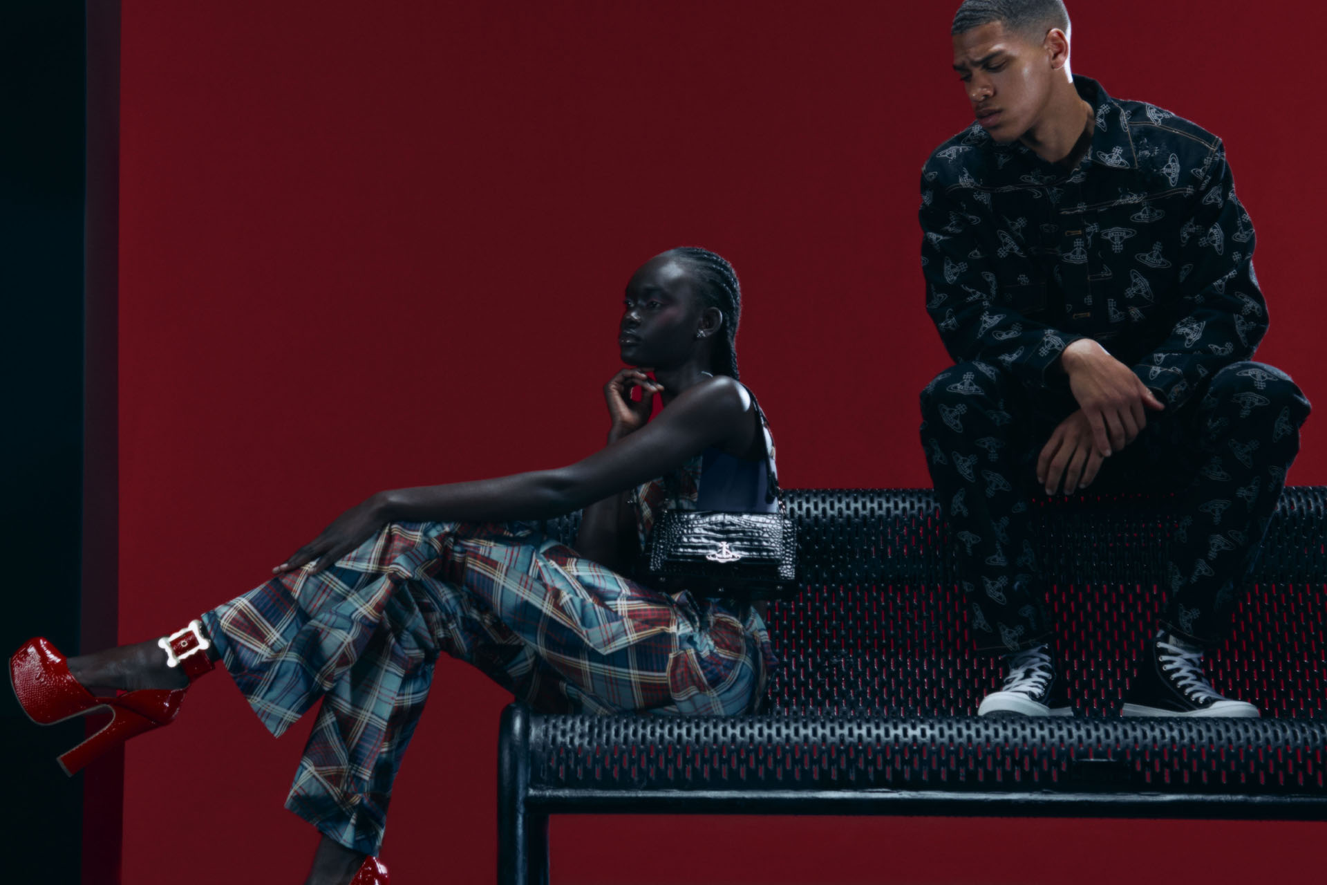 one female model and one male model sat on  a metal bench